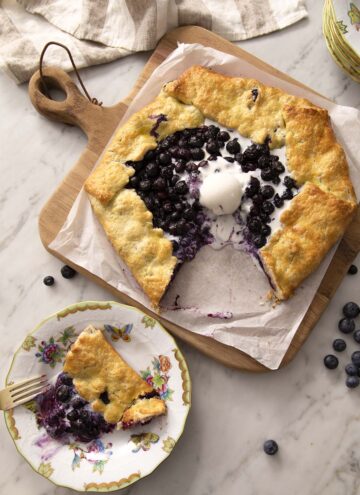 A blueberry galette with a piece removed and on a plate.