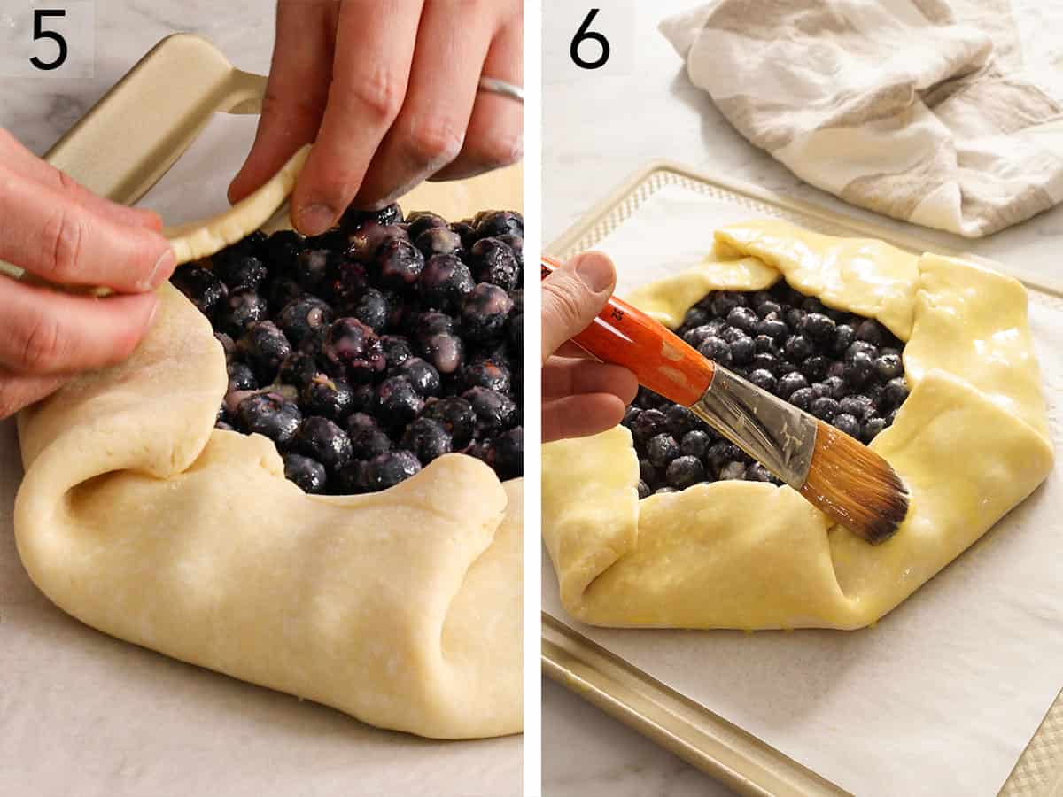 A blueberry galette getting folded and brushed with an egg wash before baking.
