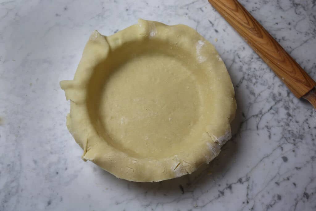 A photo of freshly made pie crust laid over a pie dish.