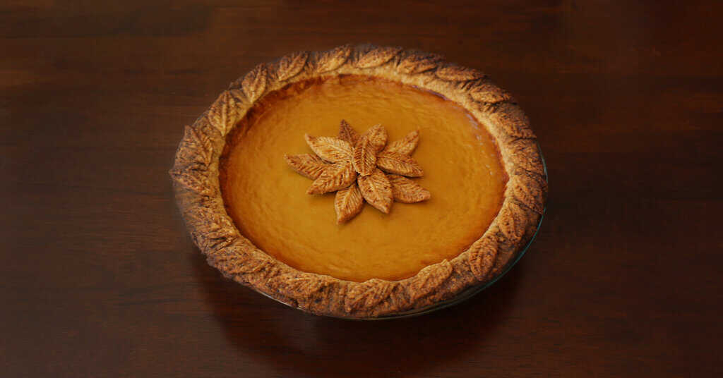 A photo of a pumpkin pie with leaves made from pie crust decorated on the middle of the cake