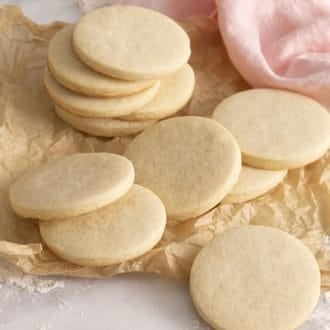 A group of round sugar cookies next to a soft pink napkin