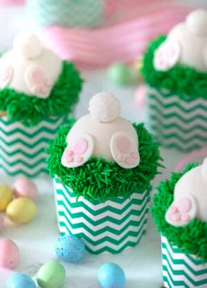 A photo of bunny butt cupcakes with chocolate eggs around them.