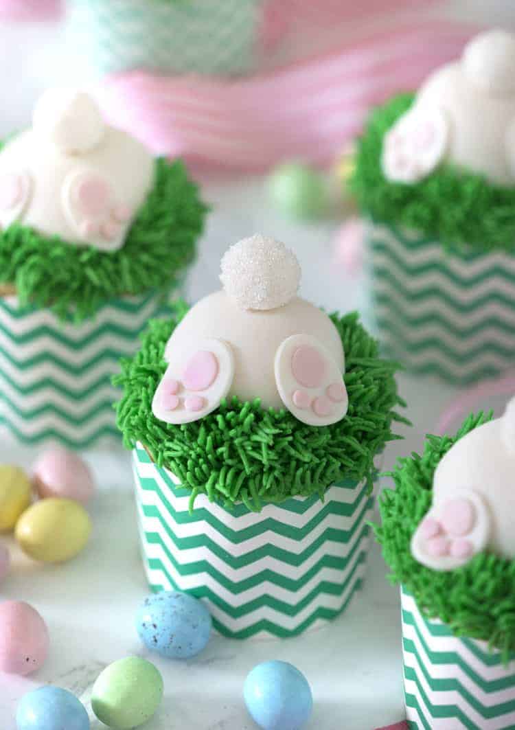 A photo of bunny butt cupcakes with chocolate eggs around them.