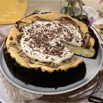 chocolate cheesecake with an Oreo crust topped with whipped cream and shaved chocolate