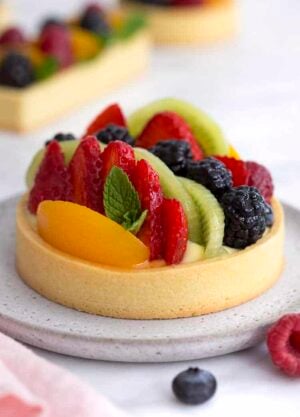 A photo of a fruit tart with various berries, peach slices and kiwis.