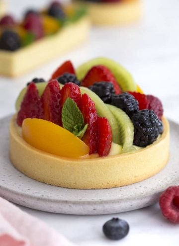 A photo of a fruit tart with various berries, peach slices and kiwis.