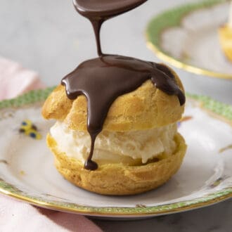 Close up of melted chocolate drizzling onto a profiterole.