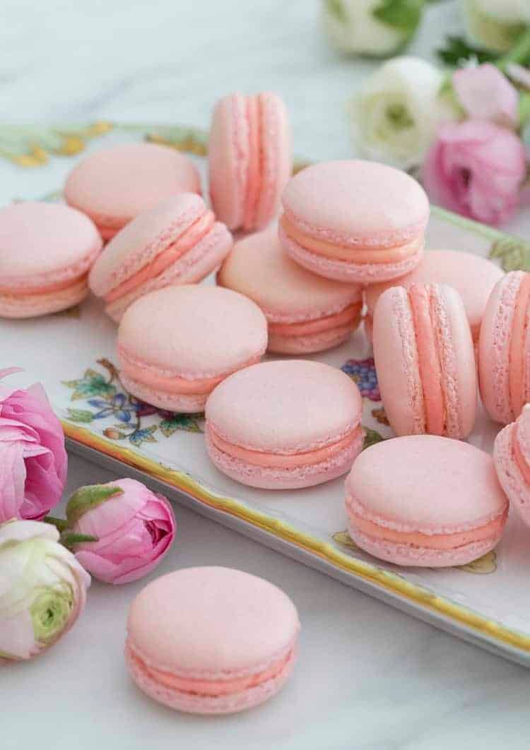 Pink french macarons on a painted porcelain plate with flowers