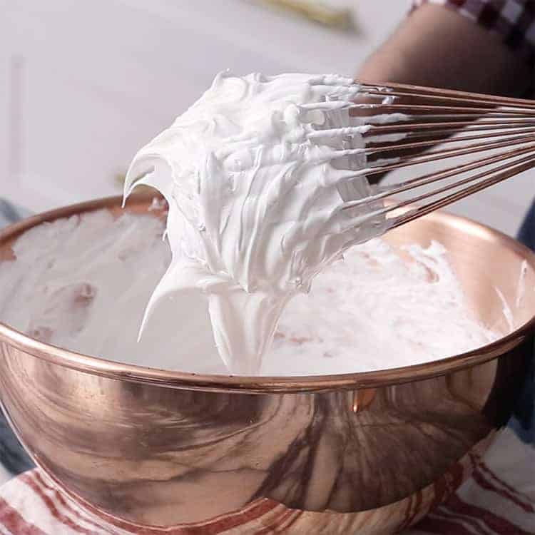 meringue whipped to stiff peaks in a copper bowl.