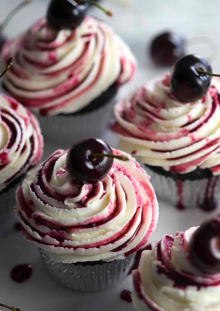 Chocolate cupcakes filled with a cherry, topped with buttercream and cherry reduction