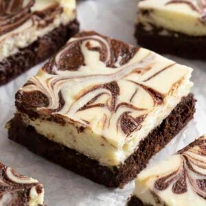 cheesecake brownies marbled with chocolate on crinkled parchment paper.