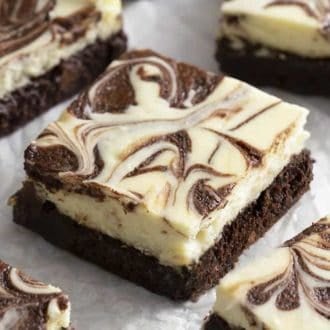cheesecake brownies marbled with chocolate on crinkled parchment paper.