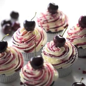 A group of chocolate cherry cupcakes on a white marble table