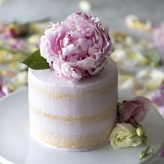 A photo of a soft pin vanilla cake topped with a beautiful peony