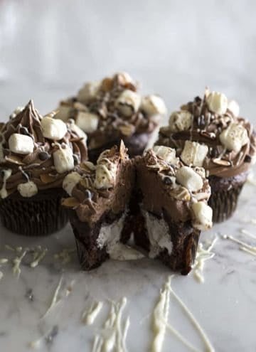 A group of rocky road cupcakes with one cut open showing a marshmallow interior