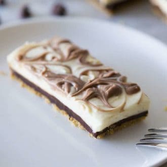 A chocolate swirled chocolate cheesecake bar on a white plate