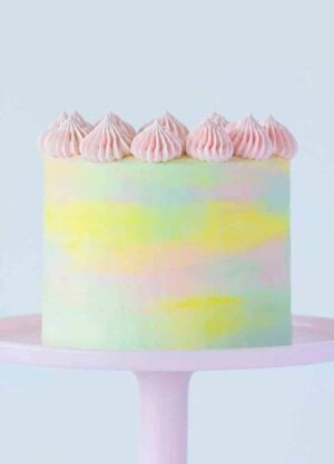A pastel watercolor cake on a pink cake stand