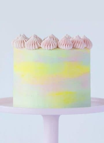 A pastel watercolor cake on a pink cake stand