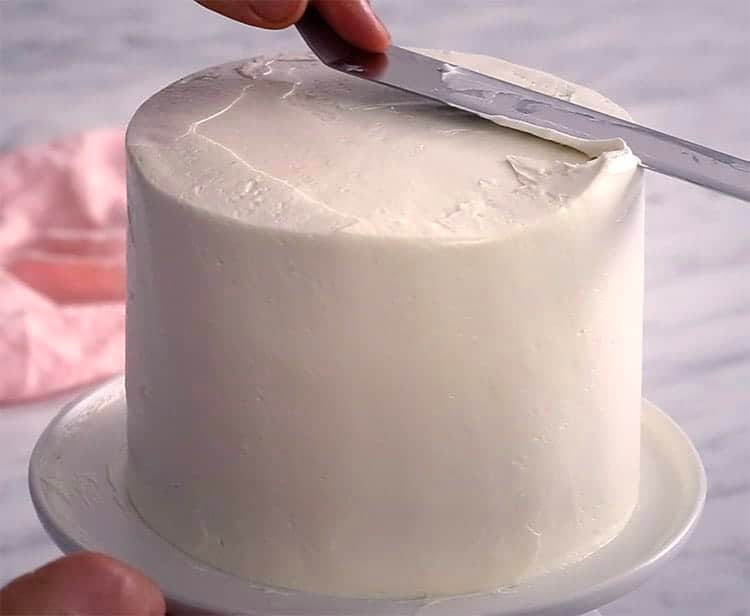 A watercolor cake having the initial smoothing with an offset spatula