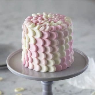 A photo of a beautiful White Chocolate Ombre Cake on a cake stand.