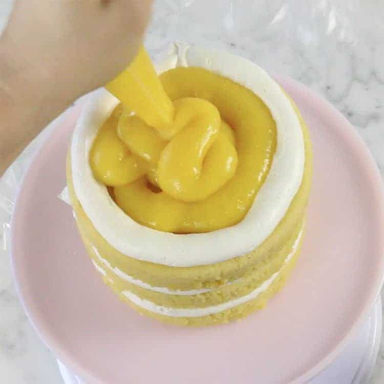 orange curd getting piped onto a cake layer