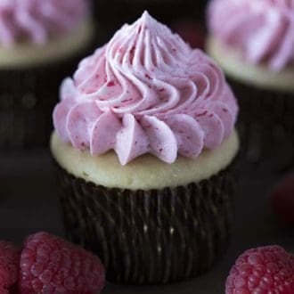 A peanut butter and jelly cupcake with raspberries in the foreground