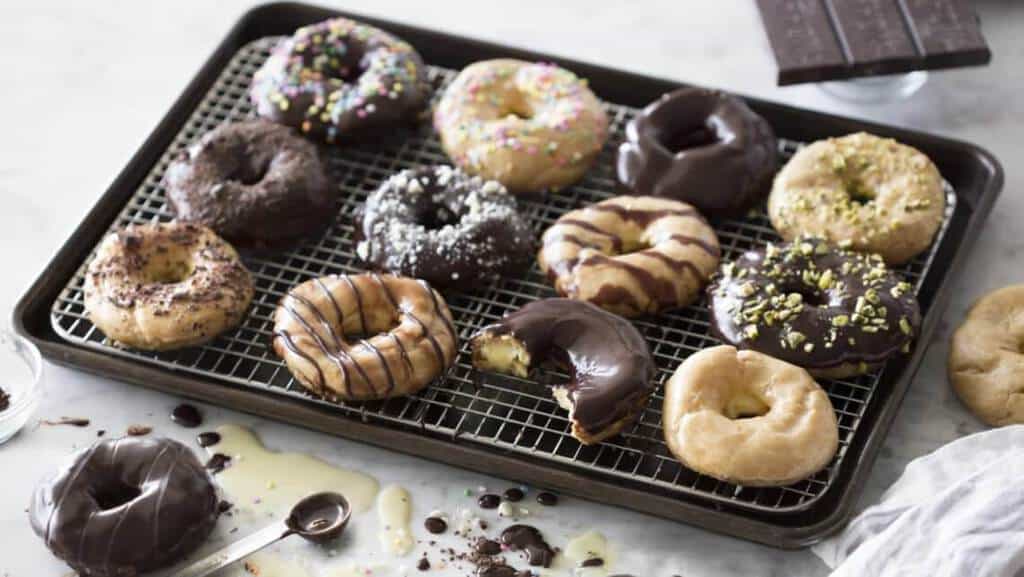 chocolate eclair donuts on a cooling rack with one cut open.