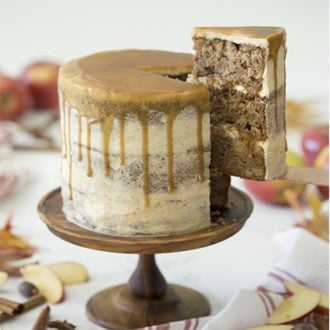 Photo of an apple spice cake with caramel on a wooden cake stand