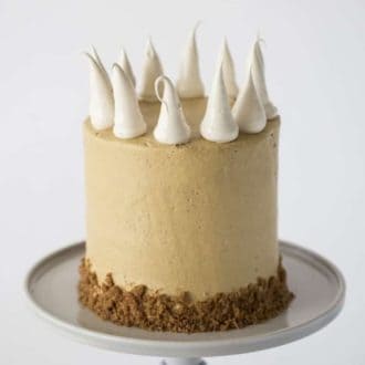 A photo of a Pumpkin Pie Cake on a cake stand with large meringue dollops.