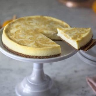 A photo of a pumpkin swirl cheesecake with a piece being removed.