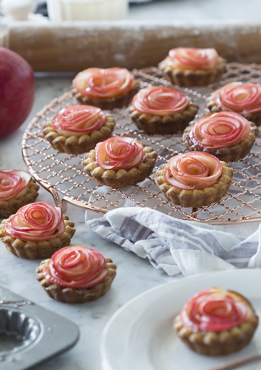 A photo of multiple apple rose tarts.