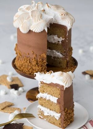 A photo of a s'mores cake with a piece on a plate ready to be served.