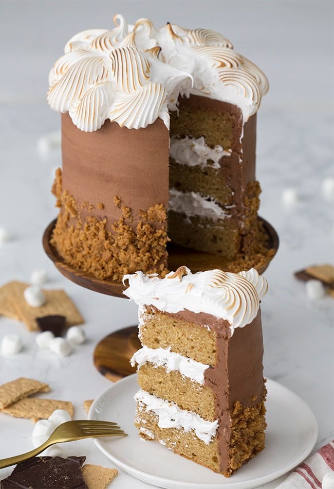 A photo of a s'mores cake with a piece on a plate ready to be served.