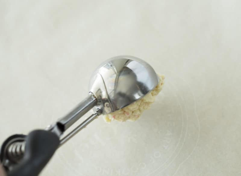 a photo cookie dough being scooped onto a pan.