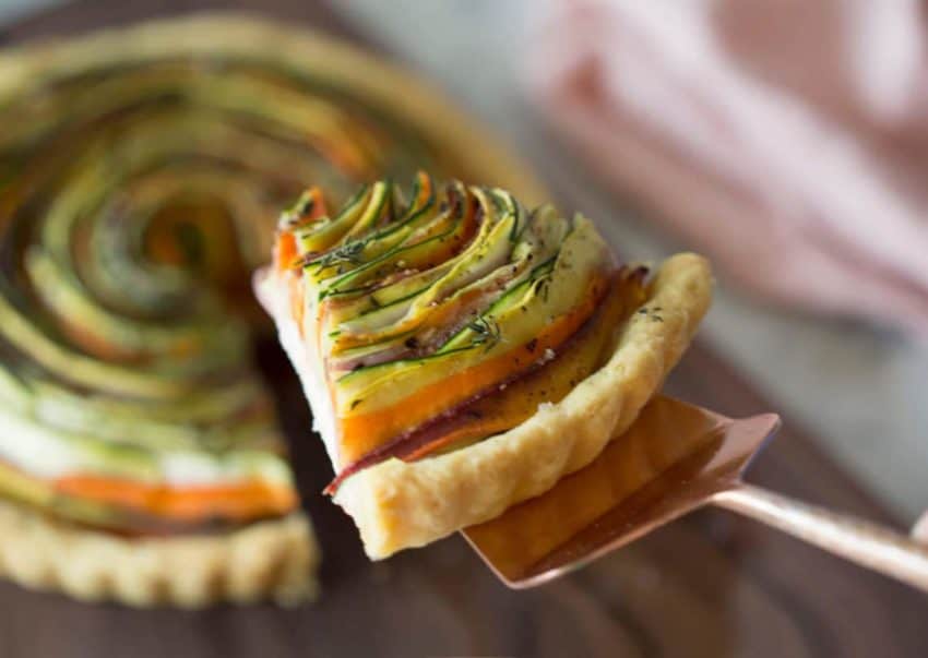 Photo of a spiral vegetable tart with a piece being removed