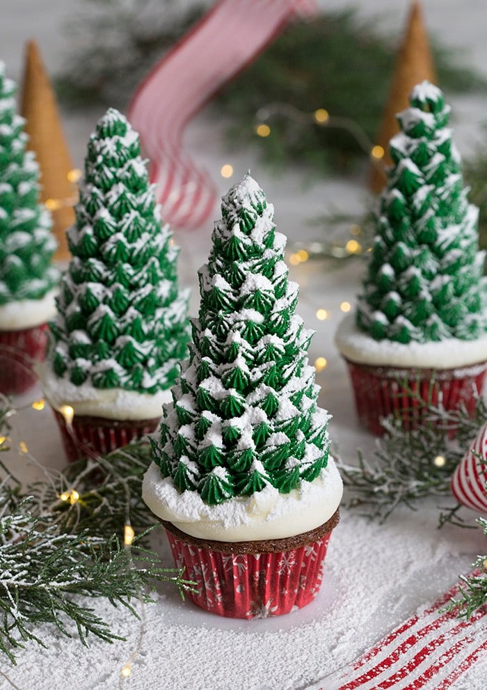 A photo of a group of Christmas tree cupcakes surrounded by pine needles.