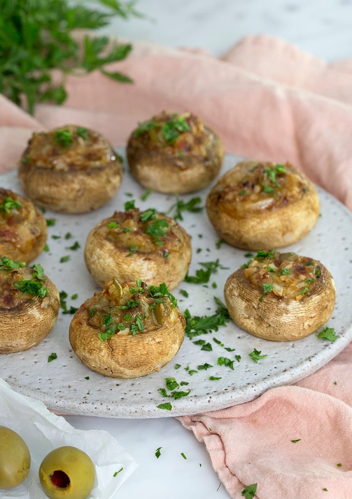 A photo of a plate of Stuffed Mushrooms sprinkled with minced parsley