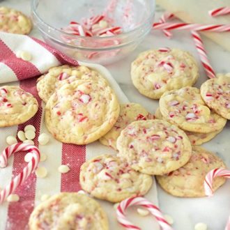A photo of a group of white chocolate candy cane cookies on a red and white towel with candy canes surrounding.