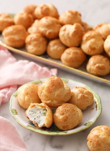 Cheese puffs on a small plate in front of a serving tray full of them