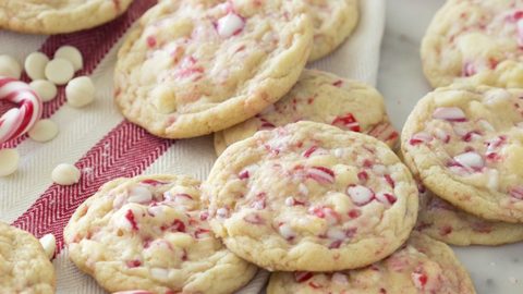 A photo of white chocolate peppermint cookies on a marble table surrounded by candy canes