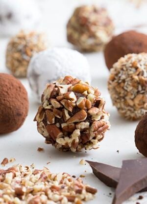 A photo of spherical brandies truffles on a white marble table.