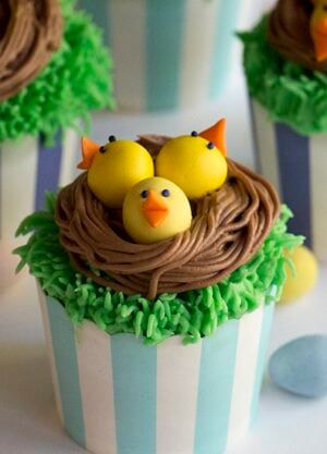 A photo showing cupcakes with baby chicks in a chocolate nest on top.