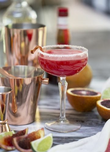 A photo of a Texas margarita in a coupe glass among copper bar tools.