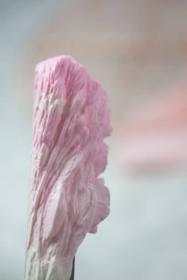 A photo showing an ombré of pink Italian buttercream on an offset spatula.