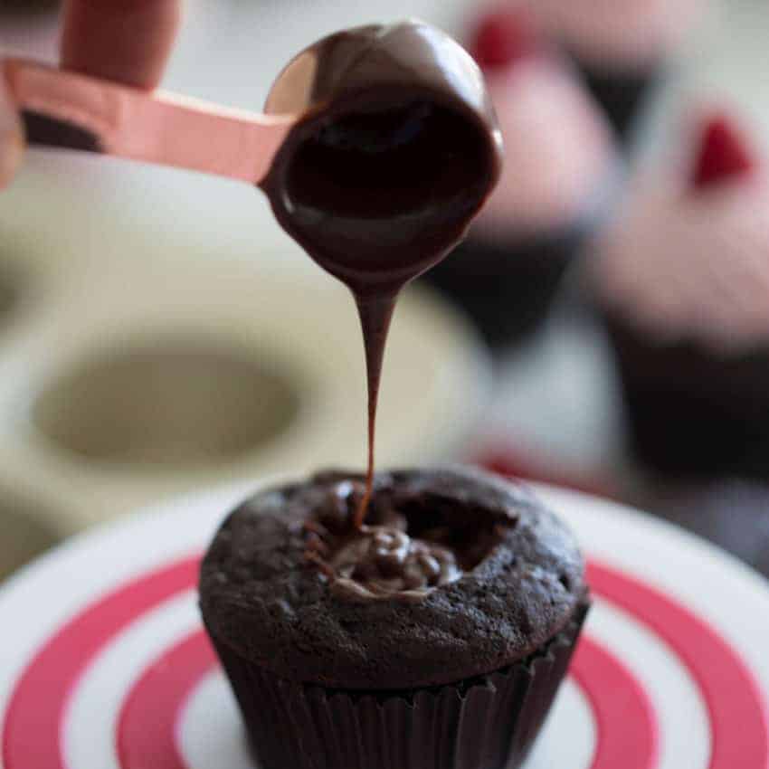 Photo of chocolate ganache being drizzled into a cupcake