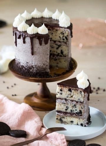 Cookies and Cream Cake on a cake stand with a piece on a plate