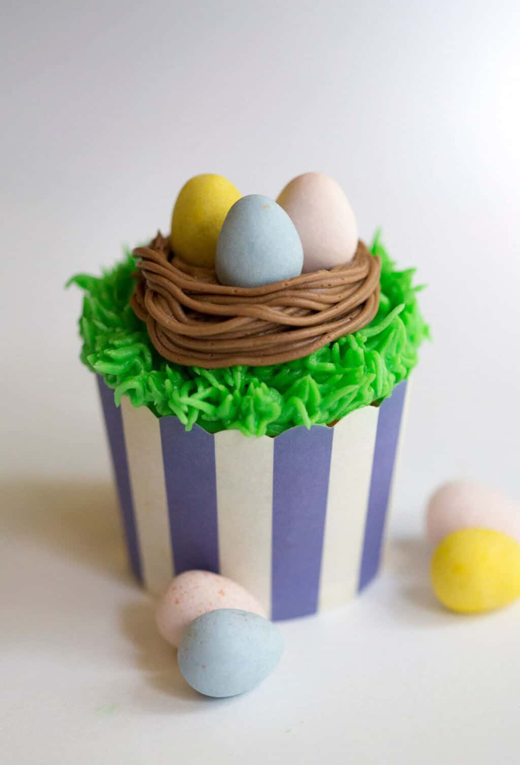 A photo of an Easter cupcake with chocolate eggs in a bird's nest.