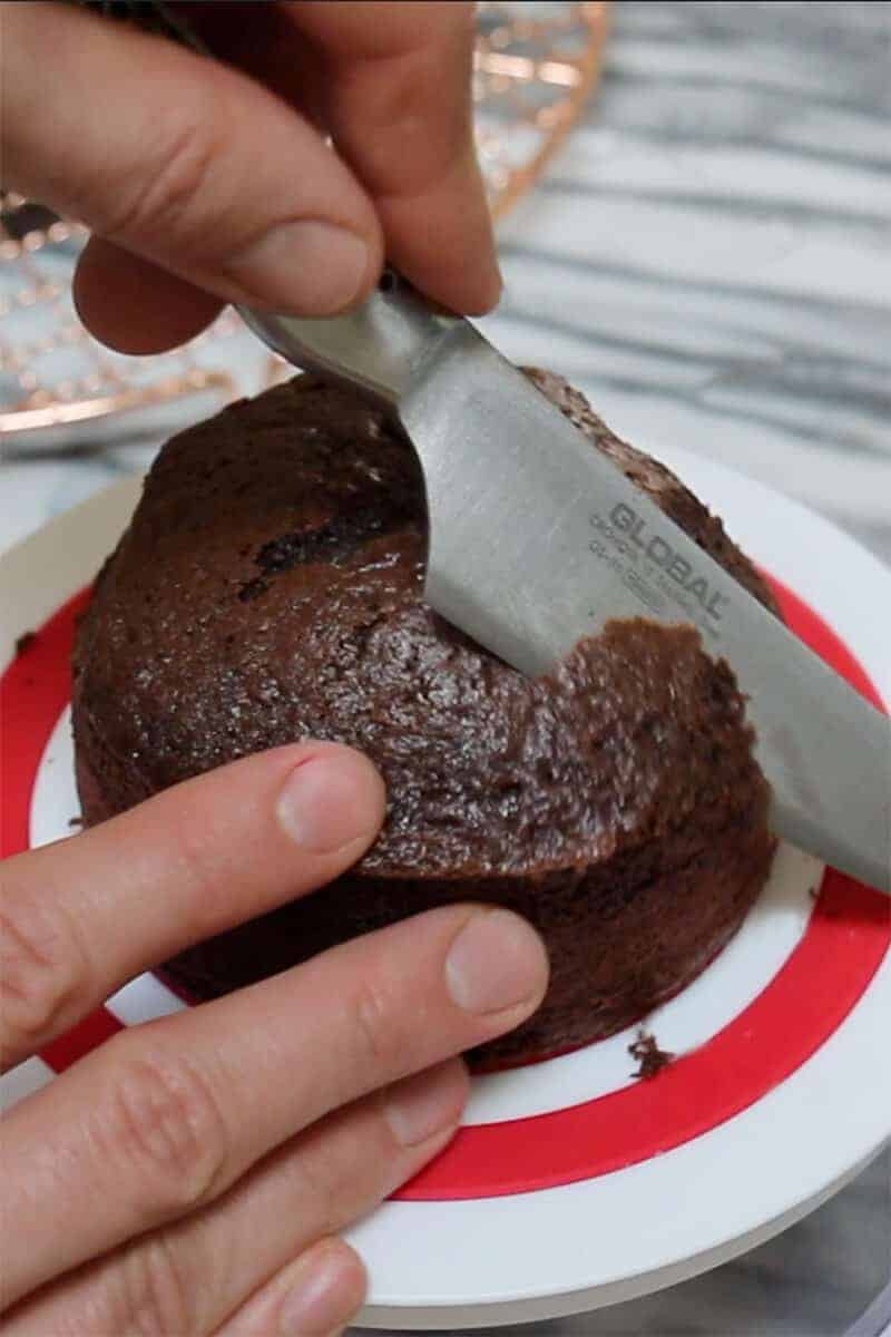 A photo showing a chocolate cake being carved into a nest shape