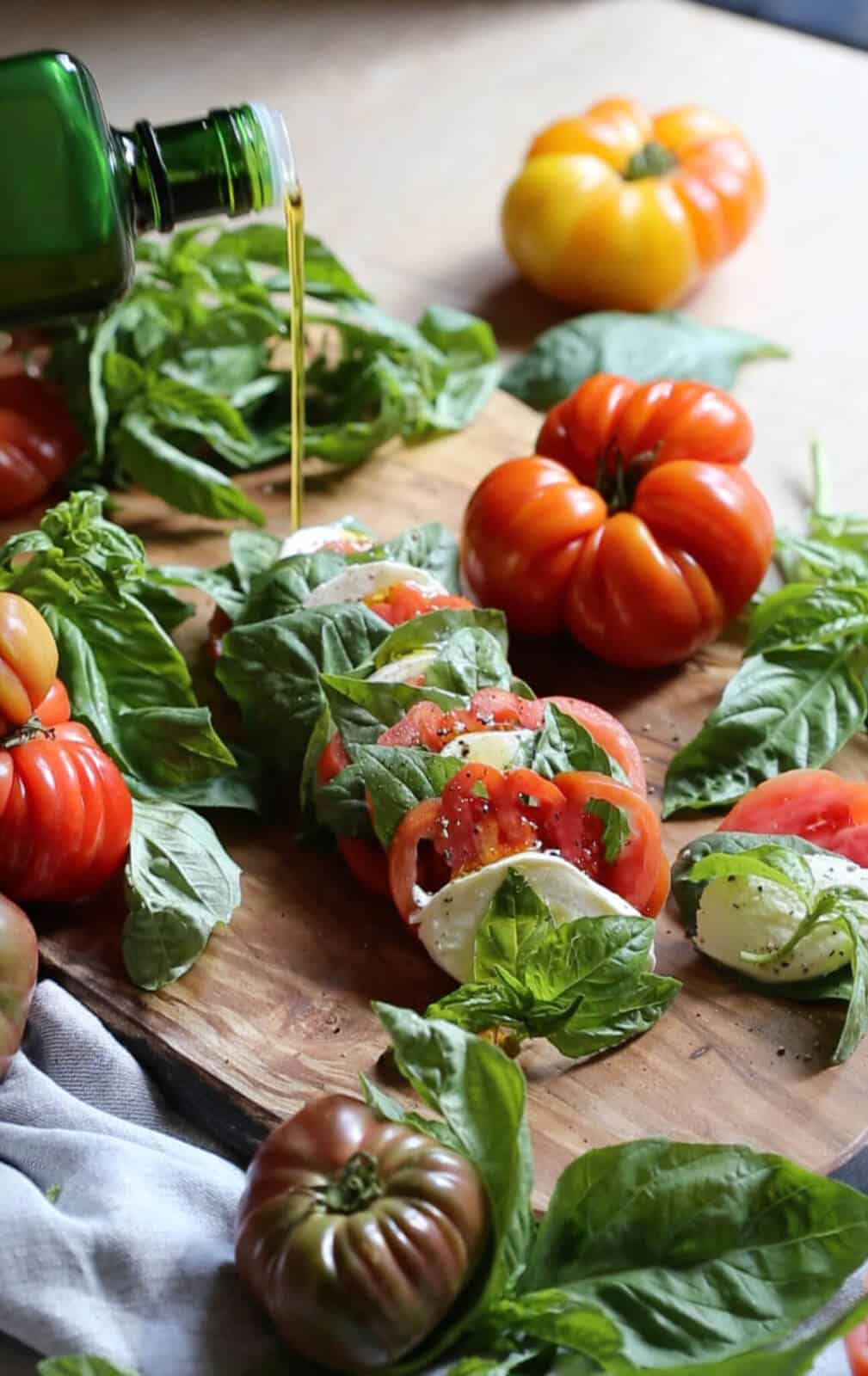 Olive oil being poured onto a caprese salad.