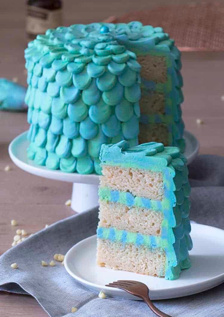 An aqua and seafoam green petaled mermaid cake with a piece in the foreground